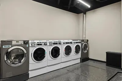 a laundry room with three washing machines in it at Freeman 1201 by Rove Travel - Studio with Shared Amenities in New York