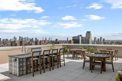 a balcony with tables and chairs and a view of the city at Freeman 503 by Rove Travel - 1BR Condo with Shared Amenities in New York