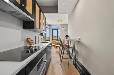 a kitchen with white walls and a counter and chairs at Freeman 903 by Rove Travel - 1BR Condo with Shared Amenities in New York