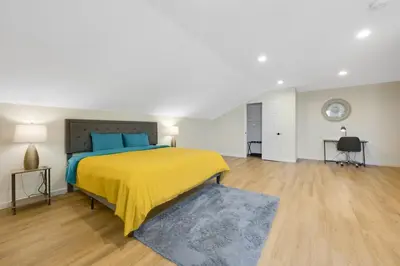 a large bedroom with a yellow bed and wooden floors at Spacious 5BR Home KING Bed Wi-Fi Parking in Bloomfield