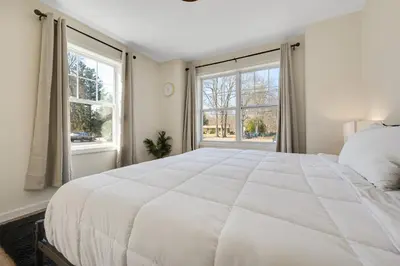 a bedroom with a large white bed and windows at Old, Unlisted in Bloomfield