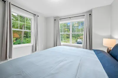 a bedroom with a large bed and two windows at Luxury 5BR Home in Central Bloomfield Spot in Bloomfield