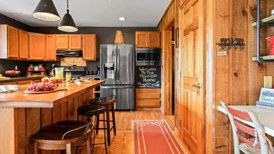 a kitchen with wooden cabinets and a stainless steel refrigerator at Discounted Winter Rates Ski Retreat Hot Tub Fire Pit Windham Mountain House in Windham