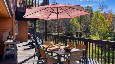 a table with a pink umbrella on a deck at Discounted Winter Rates Ski Retreat Hot Tub Fire Pit Windham Mountain House in Windham
