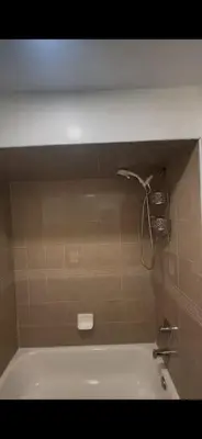 a bath tub with a shower head in a bathroom at Cozy Home 3BR-2Bath near EWR NYC DreamMall MetLife in Newark