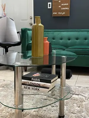 a glass coffee table with a vase on top of books at Hidden Gem BK in Brooklyn