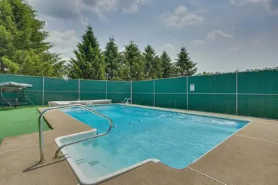 a large swimming pool with a green fence at Cottage and Suite Close to Camps and Ski Resorts in Pleasant Mount