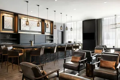a bar in a restaurant with chairs and tables at AC Hotel by Marriott Saratoga Springs in Saratoga Springs