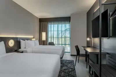 a hotel room with two beds and a desk at AC Hotel by Marriott Saratoga Springs in Saratoga Springs