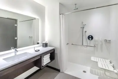 a white bathroom with a sink and a shower at AC Hotel by Marriott Saratoga Springs in Saratoga Springs