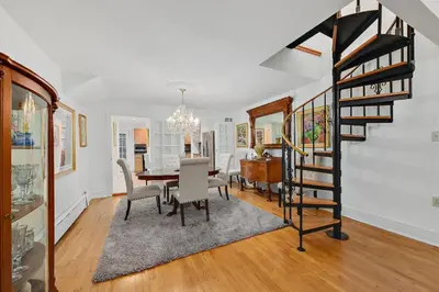 a dining room with a table and a spiral staircase at Harlem Gem in New York