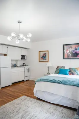 a white bedroom with a bed and a kitchen at Harlem Muse in New York