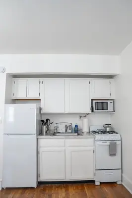 a kitchen with white cabinets and a white refrigerator at Harlem Muse in New York