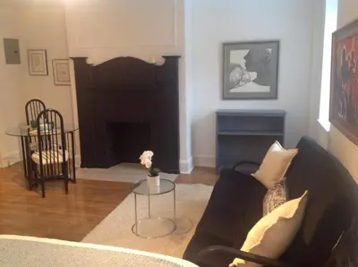 a living room with a couch and a fireplace at Historic Striver's Row Apartment in New York
