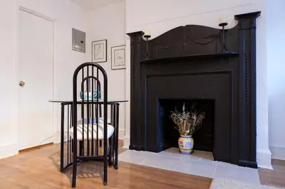 a chair sitting in front of a fireplace at Historic Striver's Row Apartment in New York