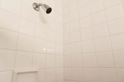 a white tiled shower with a shower head at Historic Striver's Row Apartment in New York