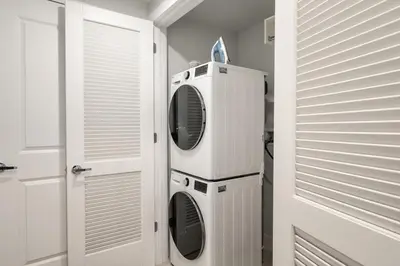 a laundry room with a washer and dryer next to a door at Sleek Loft 15 Min from NYC with Manhattan View in Jersey City