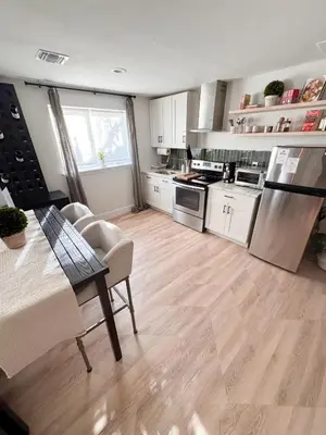 a kitchen with white cabinets and a wooden floor at New York City views! in Kearny