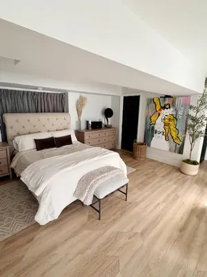 a white bedroom with a large bed and wooden floors at New York City views! in Kearny