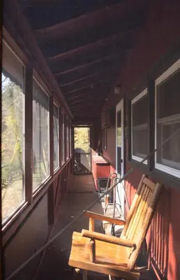 a wooden bench sitting on the porch of a house at Hot Tub, Wood-burning Fireplace and 4 acres of Forest in Margaretville in Margaretville