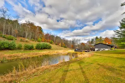 a river in a field next to a house at Hot Tub Pool & Pond - Catskills Family Escape in Cairo