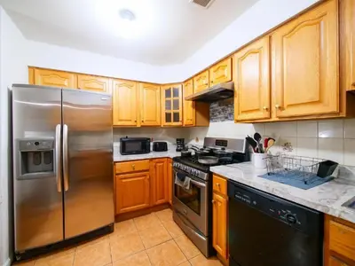 a kitchen with wooden cabinets and a stainless steel refrigerator at Charming Private Room in a Friendly Home mins to NYC in Jersey City
