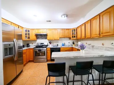 a kitchen with wooden cabinets and stainless steel appliances at Cozy Private Room with Shared Kitchen near NYC in Jersey City
