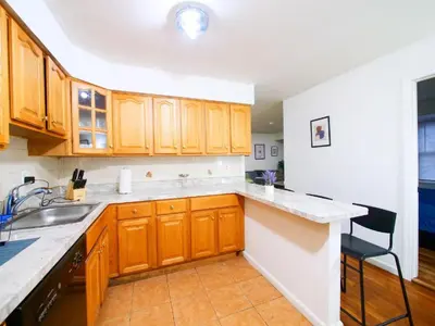 a kitchen with wooden cabinets and a sink at Mins to NYC Comfy Private Room in Shared Home in Jersey City