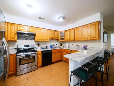 a kitchen with wooden cabinets and a stove top oven at Private Bedroom with Shared Amenities mins to NYC in Jersey City