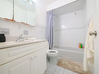 a white bathroom with a toilet and a tub and a sink at Charming Room with Shared Space close to NYC in Jersey City