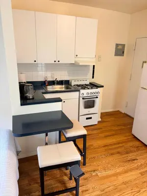 a kitchen with white cabinets and a sink and a stove at The Park Ave Studio in New York