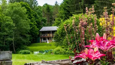 a garden with flowers and a house in the background at The Mountain Brook Inn in Bovina Center
