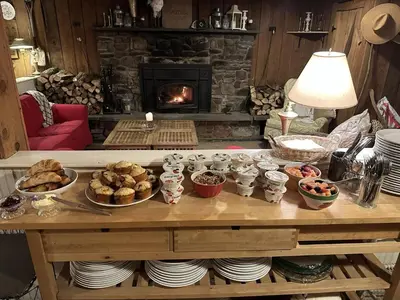 a table with plates of food and a fireplace at The Mountain Brook Inn in Bovina Center