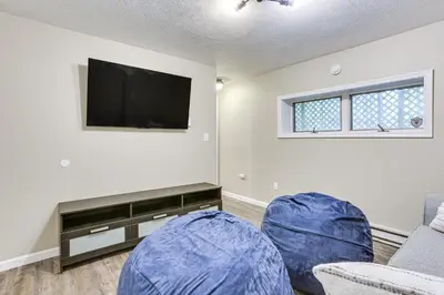 a living room with a flat screen tv and blue chairs at 6 Mi to Bushkill Falls Secluded Home with Game Room in East Stroudsburg