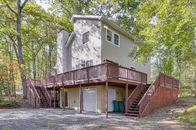 a house with a large deck on the side of it at 6 Mi to Bushkill Falls Secluded Home with Game Room in East Stroudsburg