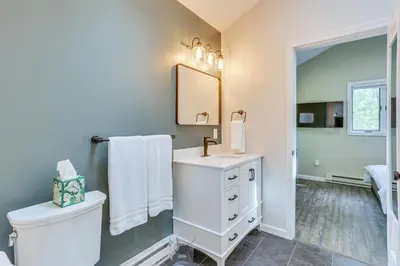 a bathroom with a toilet and a sink and a mirror at 6 Mi to Bushkill Falls Secluded Home with Game Room in East Stroudsburg