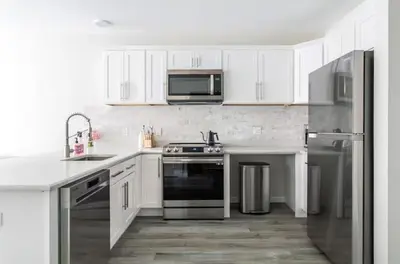 a kitchen with white cabinets and stainless steel appliances at Downtown 2BR Gem Yale Wooster Sq WiFi in New Haven