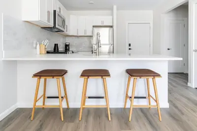 a kitchen with two wooden stools in front of a counter at Downtown 2BR Gem Yale Wooster Sq WiFi in New Haven