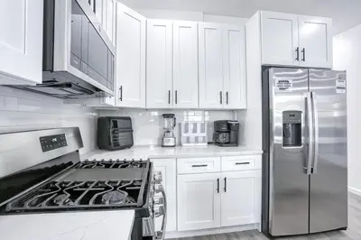 a kitchen with white cabinets and a stainless steel refrigerator at Newly Built Lake House Near NYC EWR MetLife AD Mall in Passaic