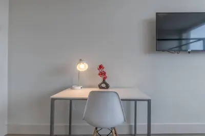 a table with a white chair and a lamp at Smoked Amber Stay, Free Parking, Sleep 5, 20 percent OFF in East Orange