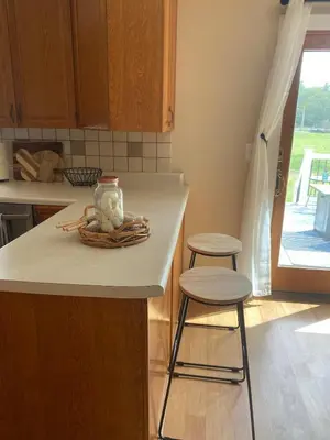 a kitchen counter with two stools and a vase on it at Cozy Creek House in Forestburgh