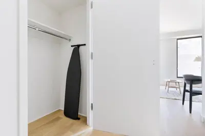 a sliding door leading into a white room with a chair at Blueground Chelsea rooftop pool nr High Line NYC-2145 in New York