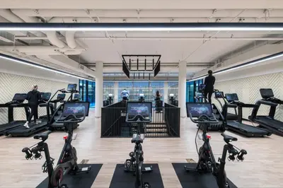 a gym with exercise bikes and people in the background at Blueground Chelsea rooftop pool nr High Line NYC-2145 in New York