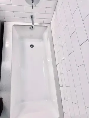 a white bath tub in a white tiled bathroom at Upper East Side 2Bed Dream in New York