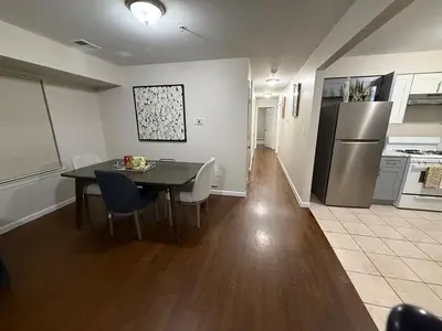 a kitchen and dining room with a table and a refrigerator at COZY 3 bedroom APT near EWR Downtown NYC in Newark