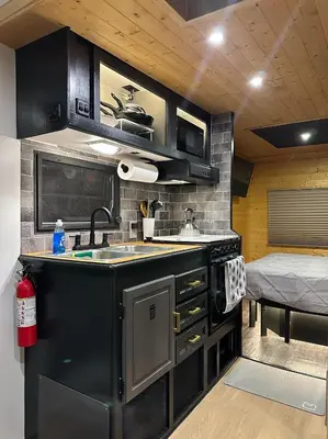 a kitchen with black cabinets and a sink and a bed at Catskill and Chill in Catskill