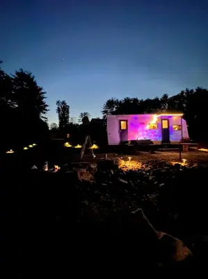 a purple lit up caravan sitting in a field at night at Catskill and Chill in Catskill