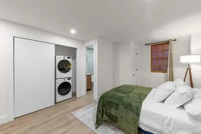 a white bedroom with a bed and two washing machines at 10-1 Stylish Townhouse Oasis in Greenpoint in Brooklyn