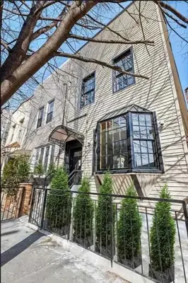 a large house with a fence in front of it at 10-1 Stylish Townhouse Oasis in Greenpoint in Brooklyn