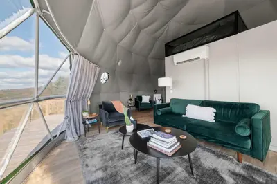 a living room with a green couch and a table at Glamping Getaway at 'The Coyote Dome' in Franklin in Franklin